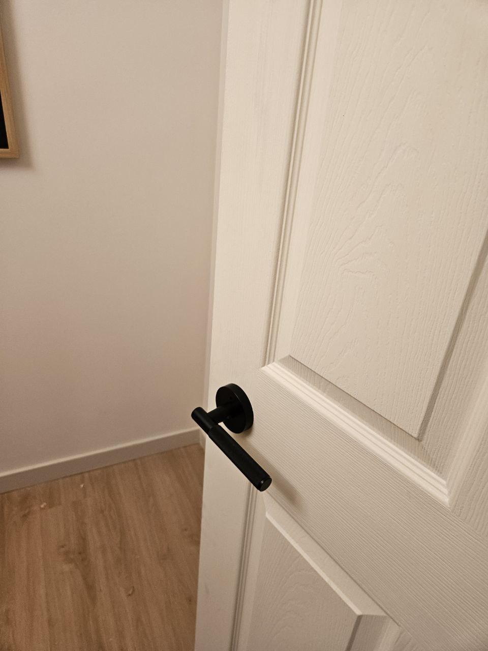 New black door handle installed on white interior door in Calgary